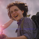 Phoebe smiles and has her hair blown back by the power of her proton pack and neutrona wand.